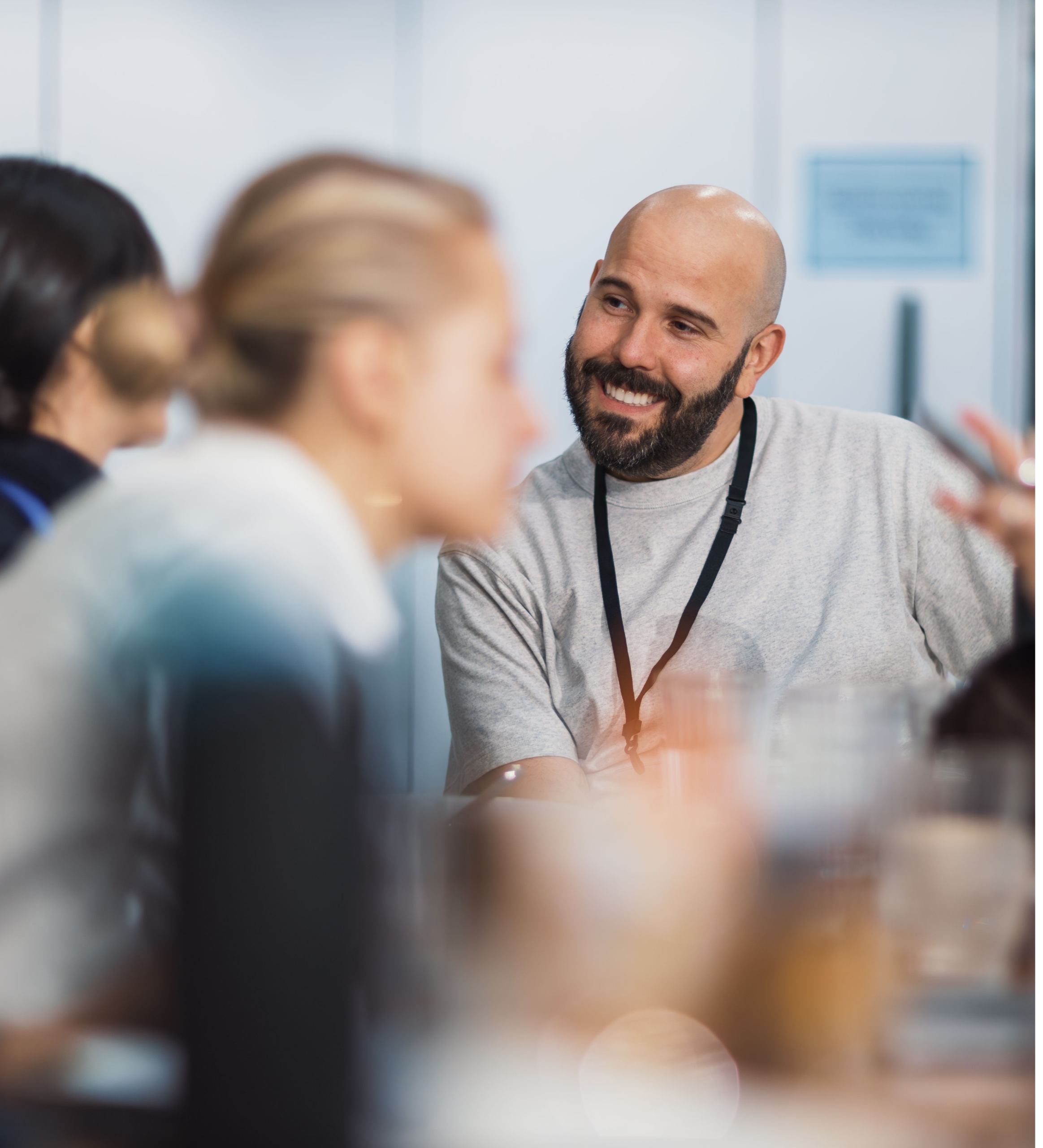 Hombre sonriente con acreditación conversando con sus compañeros en una reunión de trabajo